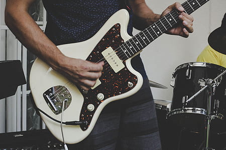 person holding white and brown electric guitar thumbnail