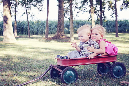 boy and girl riding on pull wagon photograph thumbnail