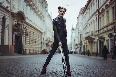 selective focus photo of woman standing on pavement holding baseball bat thumbnail