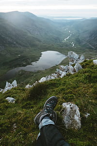 person sitting on mountain range near body of water thumbnail