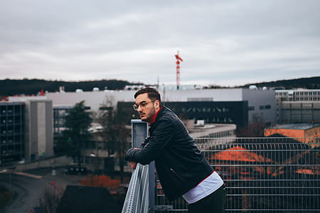 man leaning on gray metal rail thumbnail