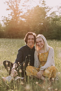 man and woman sitting on meadow during day time thumbnail