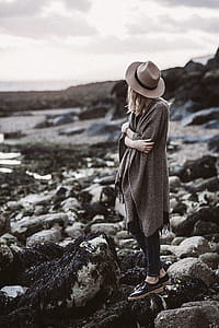 Woman Wearing Draped Coat Standing on Rock Facing Mountain thumbnail