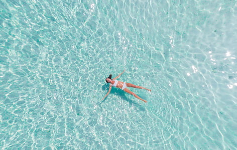 aerial photography of woman wearing white bikini set floating on body of water thumbnail