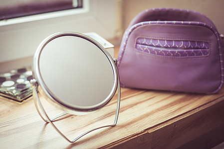 round mirror with silver frame on brown wooden table thumbnail