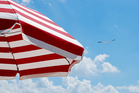 red and white striped parasol under cloudy sky thumbnail