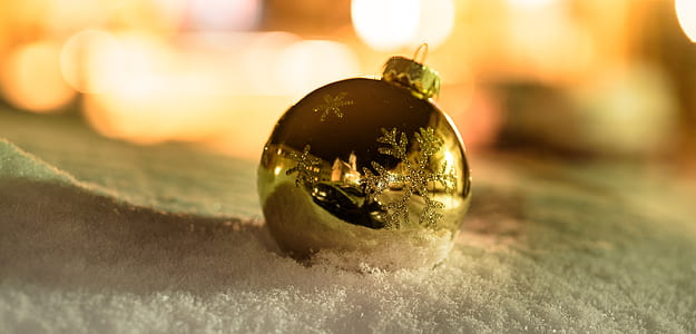 gold Christmas ornament on snow thumbnail