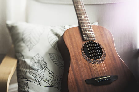 brown ukulele and white throw pillow on chair thumbnail