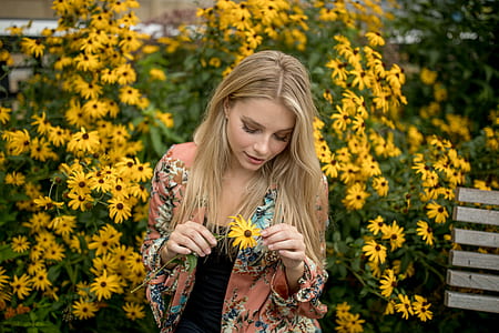 woman in pink green and yellow floral cardigan holding yellow black-eyed susan flowers thumbnail