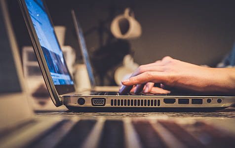 person using gray laptop on black wooden table thumbnail