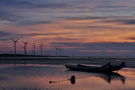 Windmills Behind Canoe Boat during Sunset thumbnail