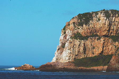 rocking mountain surrounded with sea water during day time thumbnail