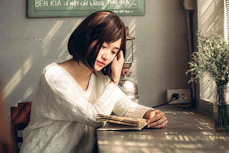 woman wearing long-sleeved shirt while reading book thumbnail