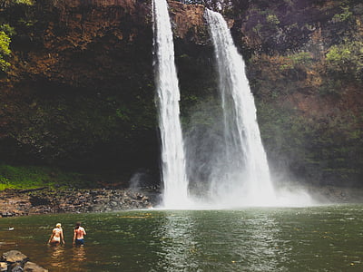 two women at body of water facing waterfalls thumbnail