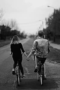 man and woman biking while holding hands thumbnail