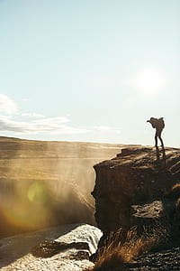 person standing on mountain cliff taking photo of surroundings thumbnail