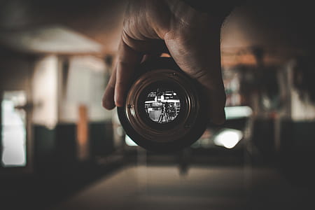 selective focus photo of person's hand holding black camera zoom lens thumbnail