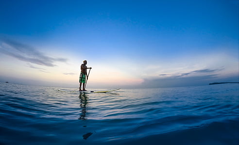 panoramic photography of man riding paddle board on body of water thumbnail