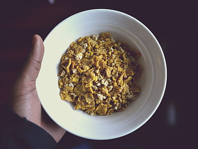 close-up photo of person holding white ceramic bowl with cereals thumbnail