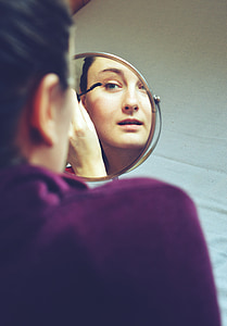 reflection of a woman having mascara on eyelashes from a mirror thumbnail