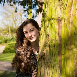 woman standing behind tree thumbnail