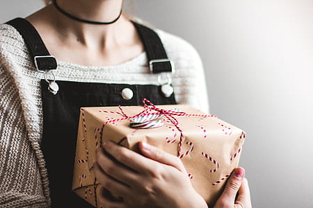 woman in black bib-and-brace top holding gift box thumbnail
