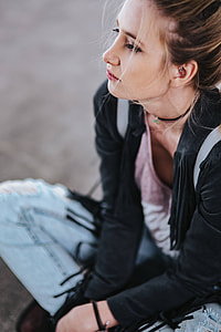 Blonde woman in a black jacket and ripped jeans by a green handrail thumbnail