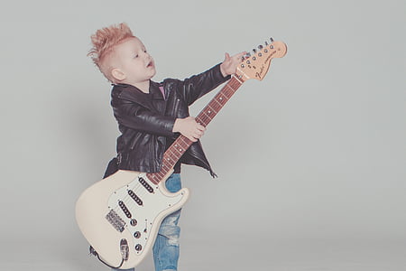 boy in black leather jacket holding white electric guitar thumbnail