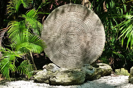 photo of round gray concrete statue near plants thumbnail