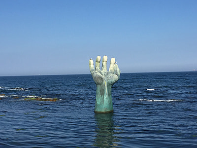 white and green concrete hand on body of water thumbnail