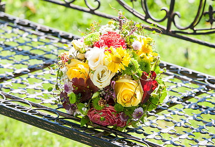 white, red, and yellow flower centerpiece on black metal bench at daytime thumbnail