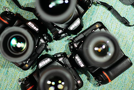 four black Nikon DSLR cameras on teal fabric sheet thumbnail