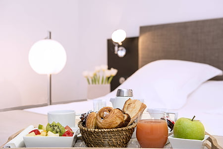 breads and fruits on brown bed serving tray on bed near table lamp thumbnail