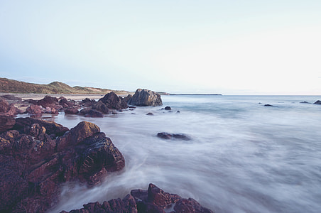 landscape photography of rocky river near green hills under blue cloudy sky thumbnail