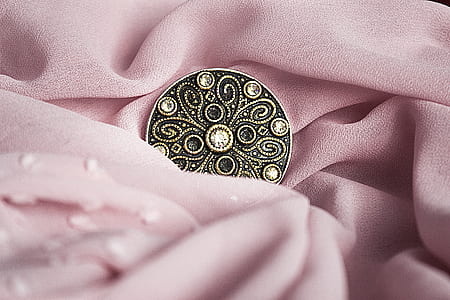 round bronze button on pink textile thumbnail