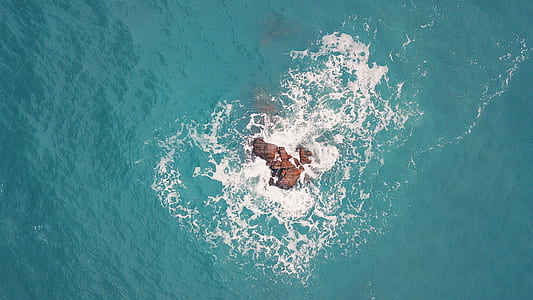 aerial shot of rock formation in the middle of body of water thumbnail