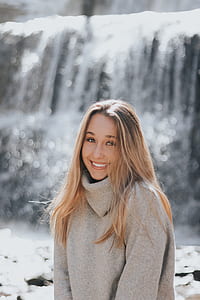smiling woman wearing grey sweater near waterfalls thumbnail