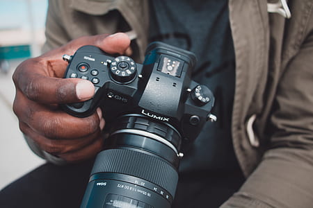 person holding black Lumix DSLR camera thumbnail