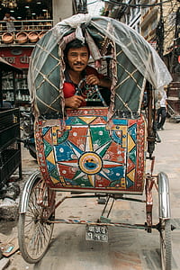 man inside cart on the road with buildings thumbnail