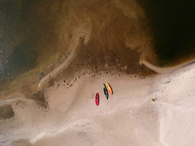 birds eye view of three assorted-color kayaks on brown sand thumbnail