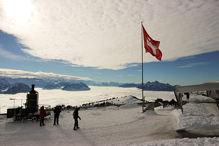 High-saturated Silhouette Photography of Three Person Standing Near Red and White Cross Printed Flag thumbnail