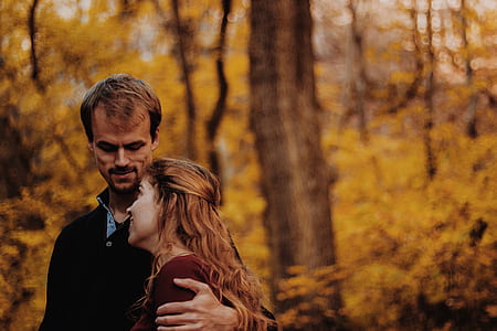 man holding girl's shoulder under brown trees thumbnail