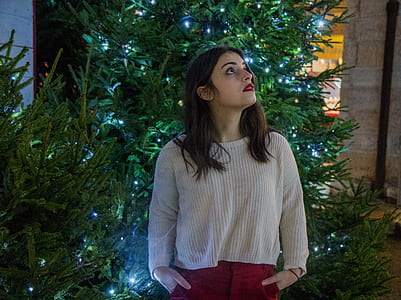 Woman Wearing White Sweater With Red Skirt Near Green Christmas Tree thumbnail