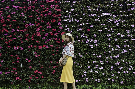 woman standing in front of pink and red petaled floral wall thumbnail