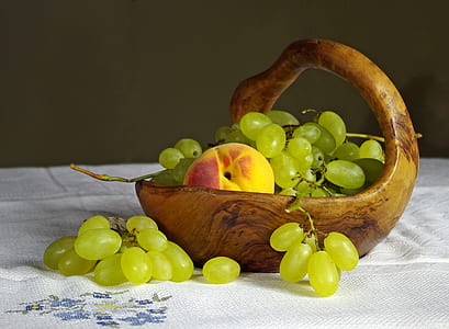 green grapes and peach fruit on white cloth and wooden basket thumbnail