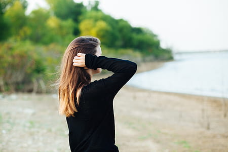 Woman Wears Black Long-sleeved Shirt Standing Near Body of Water thumbnail