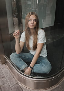 woman sitting on black surface behind glass wall thumbnail
