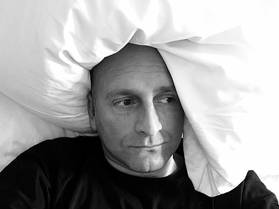 grayscale photography of man lying on bed thumbnail