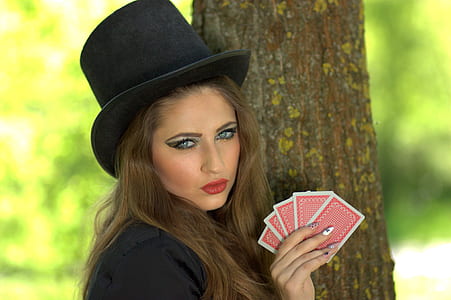 woman in black top with hat holding cards near tree thumbnail