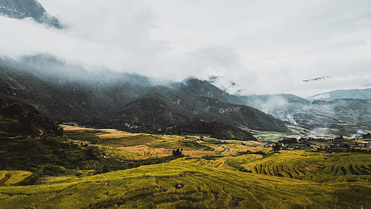 mountain near the green field under cloudy sky thumbnail